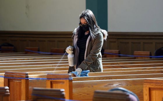 A young woman helps sanitize pews following a memorial Mass in English and Spanish on March 13 for parishioners who have died from COVID-19 at St. John-Visitation Church in the Bronx borough of New York. (CNS/Gregory A. Shemitz)