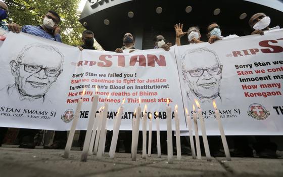 People hold a banner during a July 6 prayer service for Jesuit Fr. Stan Swamy in Mumbai, India, the day after he died at a hospital.  (CNS/Reuters/Francis Mascarenhas)