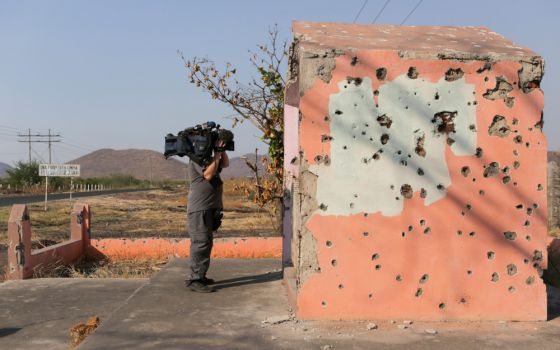 A cameraman takes video of a bullet-riddled chapel April 23 near Aguililla, Mexico. (CNS/Reuters/Alan Ortega)