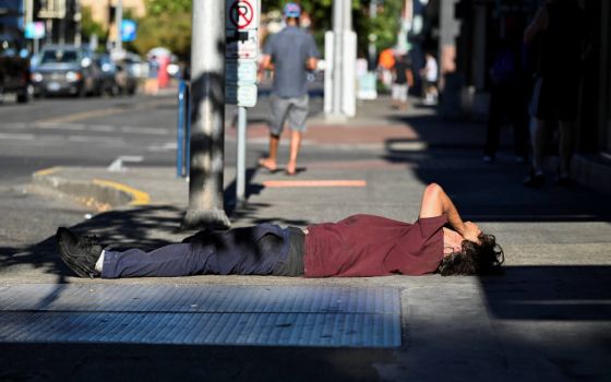 A man in Portland, Ore., lies on a sidewalk during a heatwave Aug. 11, 2021. (CNS photo/Mathieu Lewis-Rolland, Reuters)