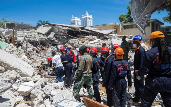 Members of a rescue and protection team clean debris from a house Aug. 15 in Les Cayes, Haiti, following a magnitude 7.2 earthquake the previous day. (CNS/Reuters/Ralph Tedy Erol)