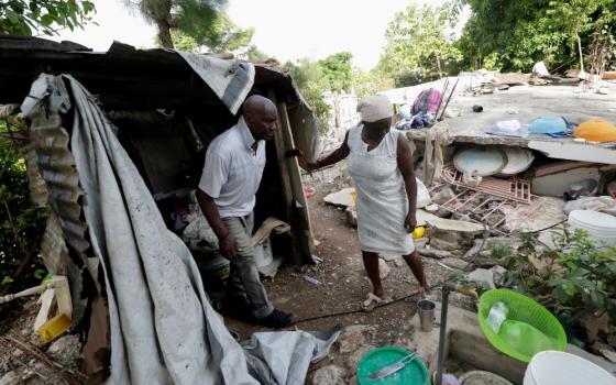 Sisters in Haiti are doing their best to continue their ministry and respond to emergency needs after the Aug. 14 earthquake. Here, Manithe Simon and his wife, Wisner Desrosier, walk through their collapsed home on Aug. 22. (CNS/Reuters/Henry Romero)