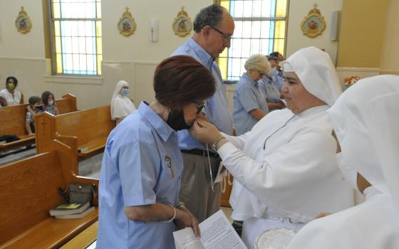 Mother Lourdes García Muñoz presents a crucifix to Elsa Villa, a former Mexican diplomat, to kiss Aug. 7 as Villa and four other laypeople pledged to assist the nuns in caring for those who are terminally ill in their homes.