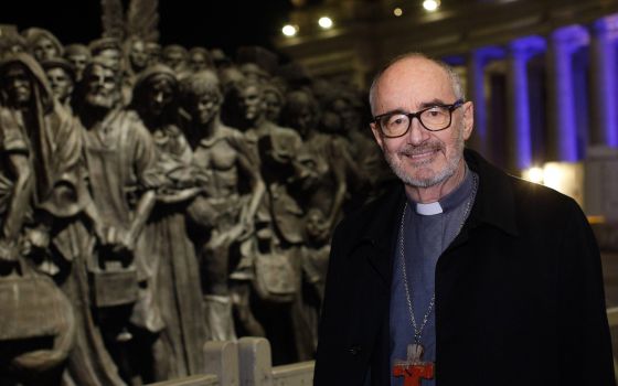 Canadian Cardinal Michael Czerny, undersecretary for migrants and refugees at the Vatican Dicastery for Promoting Integral Human Development, poses for a photo at the "Angels Unawares" statue in St. Peter's Square at the Vatican Dec. 15, 2020. In a virtua