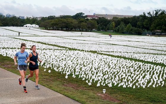 Women in Washington run past an exhibition of white flags at the National Mall Sept. 17, that represent Americans who have died of the coronavirus disease. (CNS/Reuters/Joshua Roberts)