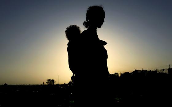 An Ethiopian woman who fled the ongoing fighting in Tigray region, carries her child near the Setit river on the Sudan-Ethiopia border Nov. 22, 2020. (CNS/Reuters/Mohamed Nureldin Abdallah)