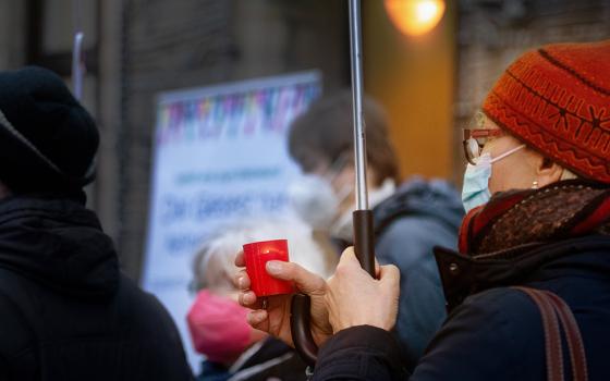 A woman holds a candle during a rally for victims of clerical sexual abuse Jan. 21 in front of the cathedral in Essen, Germany. (CNS/KNA/Andre Zelck)