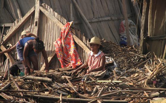 A Malagasy family is pictured outside their destroyed home Feb. 8 in Mananjary, Madagascar, in the aftermath of Cyclone Batsirai. Ahead of COP27, some organizations in Africa plan to call for compensation for the damage climate change has already exacerbated. (CNS/Courtesy of CRS) 