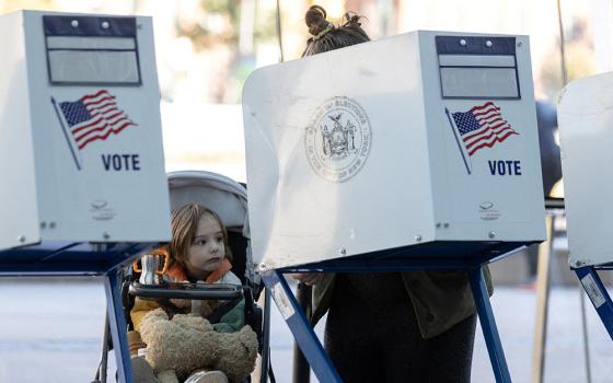 A girl at the Brooklyn Museum in New York City watches her mother cast her ballot during early voting Oct. 29. (CNS/Reuters/Jeenah Moon)