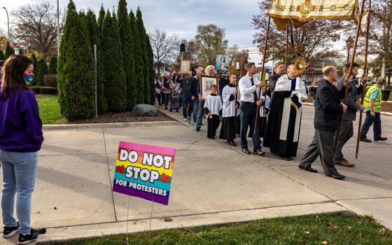 An abortion clinic escort watches a Catholic procession pass Northland Family Planning in Westland, Michigan, Nov. 5, 2022, to demonstrate against a ballot measure known as Proposal 3, which would codify a right to abortion. Michigan voters approved the measure in the Nov. 8 midterm election. (CNS/Reuters/Evelyn Hockstein)