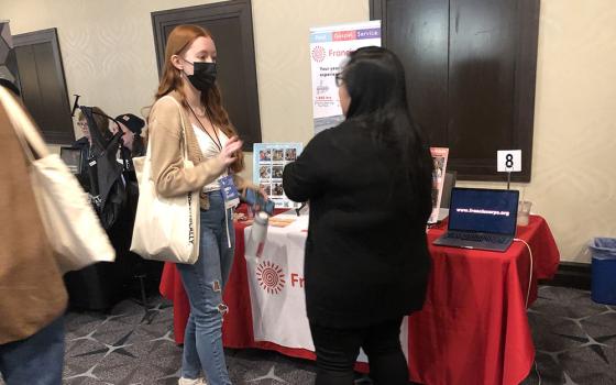 Jenny Rose Anacan, associate director of FrancisCorps, talks with Isabelle Marinchik at the FrancisCorps table at the Ignatian Family Teach-In for Justice in Washington, D.C., Oct. 23. (NCR photo/Aleja Hertzler-McCain)
