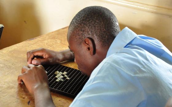 Boy uses board and tiles to solve math problem. 