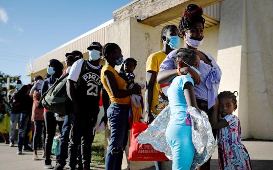 Migrants released from U.S. Customs and Border Protection in Del Rio, Texas, wait in line to board a bus to Houston Sept. 24, 2021. (CNS/Reuters/Marco Bello)