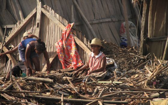 A Malagasy family is pictured outside their destroyed home Feb. 8, 2022, in Mananjary, Madagascar, in the aftermath of Cyclone Batsirai. (CNS/courtesy CRS)