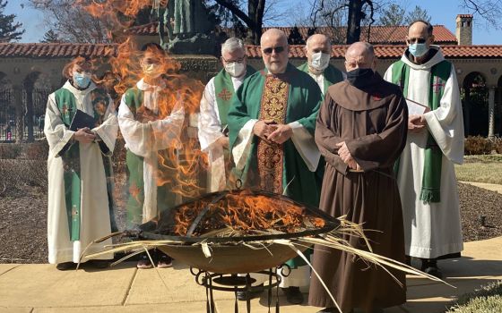 A group of friars from the Franciscan Monastery of the Holy Land in Washington look on Feb. 27, 2022, as a fire burns out after turning last year's Palm Sunday palms into ashes. (CNS photo/Rhina Guidos)