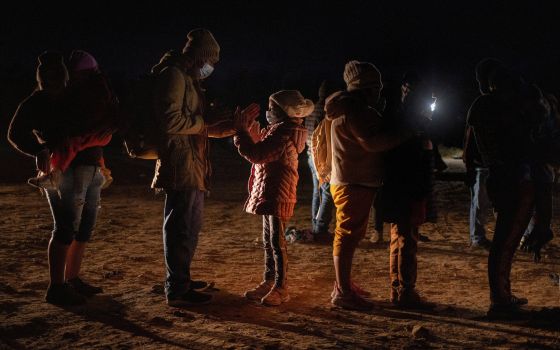 Romando, a migrant from Peru seeking asylum in the United States, plays a hand-clapping game with his daughter Alexa, 7, as they stand in line waiting to be processed in Roma, Texas, Feb. 28, 2022. (CNS photo/Adrees Latif, Reuters)