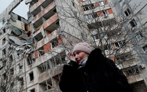 A woman reacts in front of destroyed apartment buildings in Mariupol, Ukraine, March 17, 2022.