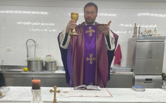 Archbishop Visvaldas Kulbokas, apostolic nuncio to Ukraine, elevates the Eucharist in the kitchen at the apostolic nunciature in Kyiv, Ukraine, in this recent photo. During the war, Archbishop Kulbokas has been celebrating Mass in the kitchen because it's