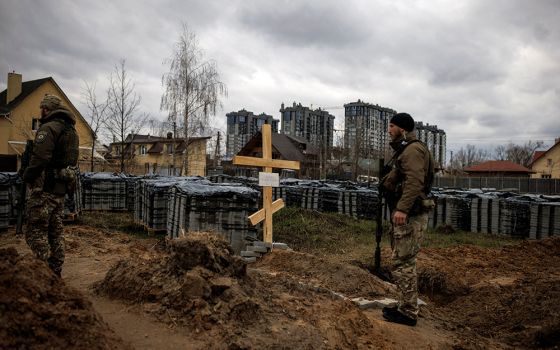 Ukrainian soldiers stand next to the grave of a civilian April 6 in Bucha, Ukraine. Local residents said the civilian was killed by Russian soldiers during Russia's invasion of Ukraine. (CNS/Reuters/Alkis Konstantinidis)