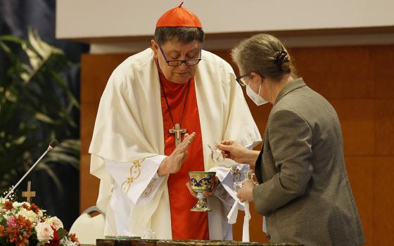 Cardinal João Braz de Aviz is assisted by Comboni Sr. Gabriella Bottani during a May 3 Mass with superiors of women's religious orders at the plenary assembly of the International Union of Superior Generals in Rome. (CNS/Paul Haring)