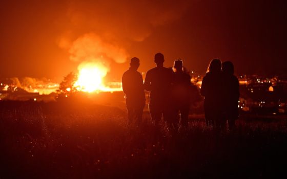 People watch as the completed Craigyhill bonfire burns on the '11th night' to usher in the 12th of July celebrations in Larne, Northern Ireland, July 11. (CNS/Reuters/Clodagh Kilcoyne)