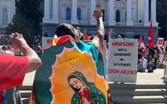 A marcher wearing an Our Lady of Guadelupe flag in Sacramento, Calif., stands in front of the state capitol building Aug. 26, 2022