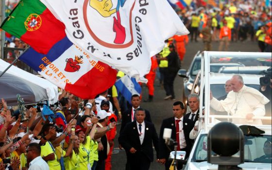 A Portuguese flag is seen near Pope Francis as he greets the crowd before celebrating Mass for World Youth Day pilgrims in Panama City