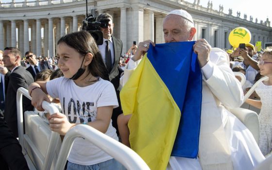 Pope Francis holds a Ukrainian flag as he greets the crowd before Mass in St. Peter's Square during the World Meeting of Families at the Vatican in this June 25, 2022, file photo.