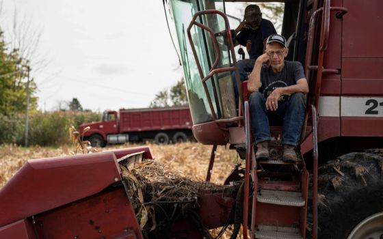 Dale Nething, 86, of Ravenna, Ohio, waits on the steps of his combine Oct. 11, 2021, as his son Don Nething, 62, troubleshoots the harvester after it breaks down. (CNS photo/Dane Rhys, Reuters)