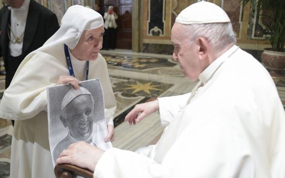 Pope Francis looks at artwork of himself presented by a nun during an audience with the participants of a symposium on "Holiness Today," sponsored by the Dicastery for the Causes of Saints, at the Vatican Oct. 6, 2022