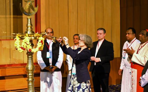 Woman lights candle while group looks on