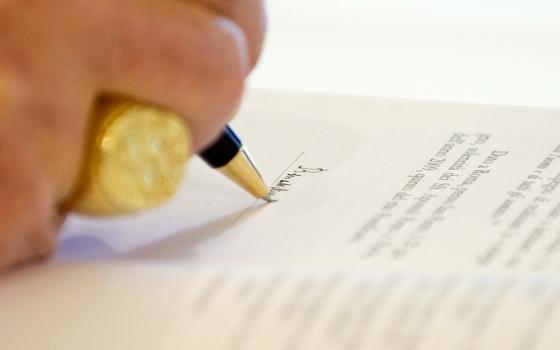 Pope Benedict XVI signs a copy of his encyclical Caritas in Veritate ("Charity in Truth") at the Vatican July 6, 2009. (CNS/L'Osservatore Romano via Reuters)