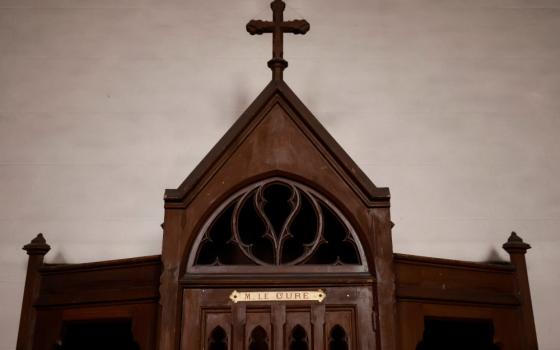 A brown confessional with a cross on the top