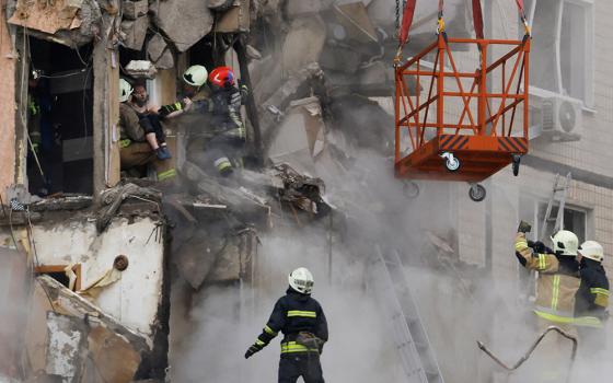 Emergency personnel evacuate a person Jan. 15 from a building in an apartment block that was heavily damaged by a Russian missile strike in Dnipro, Ukraine. (OSV News/Reuters/Clodagh Kilcoyne)