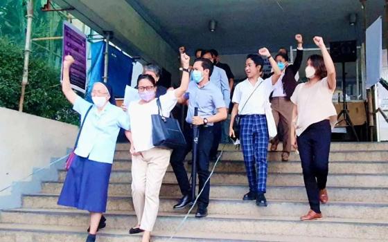 A group of Filipino people with their fists raised stand on steps of a courthouse in Manila