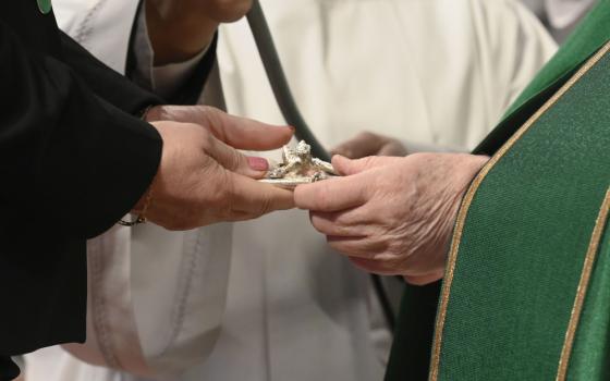 Pope Francis gives a crucifix to a layperson he installed as a catechist Jan. 23 during a Mass in St. Peter's Basilica at the Vatican. The Dicastery for Laity, the Family and Life is sponsoring a conference aimed at promoting the "co-responsibility" of laypeople and clergy for the life of the church and its mission in the world. (CNS/Vatican Media)