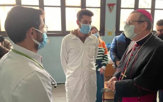 A masked archbishop talks to two Turkish doctors with white coats and masks