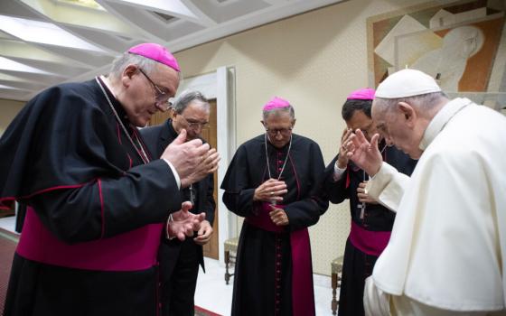 Pope Francis and four bishops stand in a circle with bowed heads as they make the sign of the cross