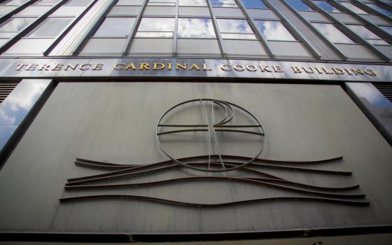 The front of a tall building with a cross and the words Terrance Cardinal Cookie Building