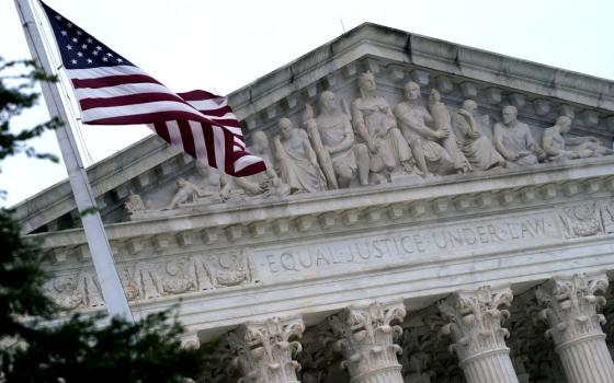 The top of the Supreme Court building with an American flag, the upper parts of the columns, and the roof