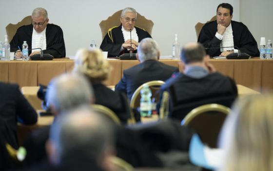 Three white men sit above a larger room wearing white ruffled shirts and black jackets