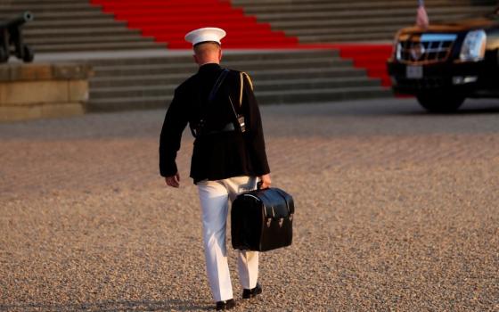 A U.S. military aide in Woodstock, Britain, carries the "football" containing launch codes for nuclear weapons into Blenheim Palace July 12, 2018, where former President Donald Trump and first lady Melania Trump were dining. (CNS/Reuters/Kevin Lamarque)