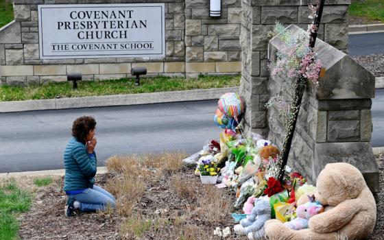 A woman prays in front of a makeshift memorial in Nashville, Tennessee, March 28, by the entrance of the Covenant School the day after a mass shooting. Three adults and three children, all 9 years old, were fatally shot at the school. (OSV News/USA Today Network via Reuters/Mark Zaleski)