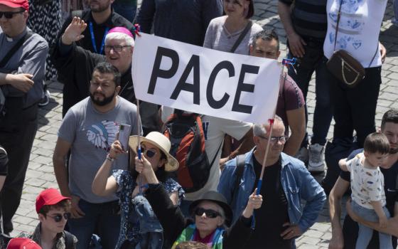 People hold up a sign saying, "Peace," as they join Pope Francis for the midday recitation of the "Regina Coeli" prayer in St. Peter's Square at the Vatican May 21, 2023. (CNS photo/Vatican Media)