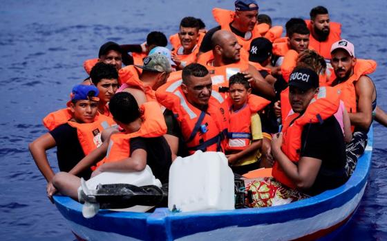 Migrants on a wooden boat wait for the Italian Guardia Costiera near the island of Lampedusa, in the Mediterranean Sea, Sept. 1, 2021.