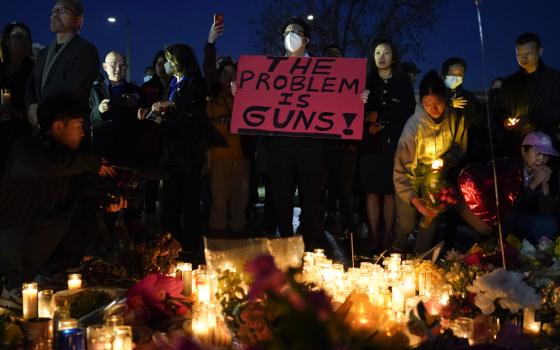 A man holds a sign during a vigil outside Monterey Park City Hall, blocks from the Star Ballroom Dance Studio, Jan. 24, in Monterey Park, California. (AP/Ashley Landis)