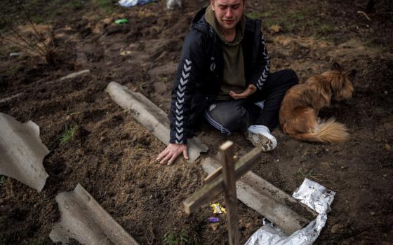 Serhii Lahovskyi, 26, mourns next to the grave of his friend, Ihor Lytvynenko, after he was beside a building's basement in Bucha, Ukraine, April 6, 2022. Residents say the man was killed by Russian soldiers. (CNS/Reuters/Alkis Konstantinidis)