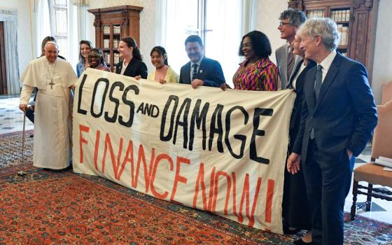 Pope Francis joins others in holding a banner during an audience at the Vatican June 5, 2023, with the organizers of the Green & Blue Festival. The banner calls for financing a "loss and damage" fund that was agreed upon at the COP27 U.N. climate conference in 2022.