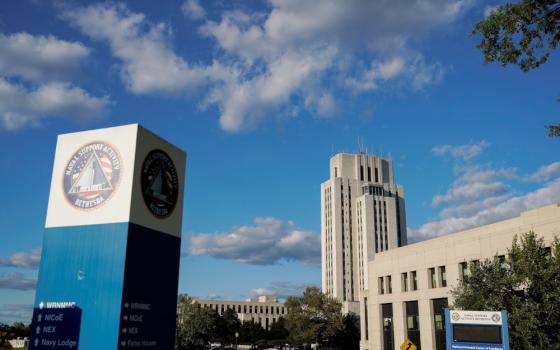 A large blue and white pillar says "Naval support activity Bethesda." It stands in front of a tall concrete building with windows