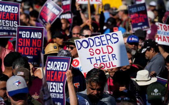 Protesters hold signs that read "Dodgers sold their soul"